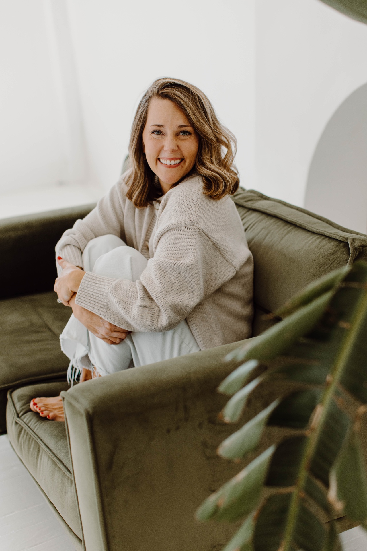 Lacey smiling, sitting on an olive green couch